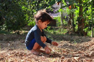 Side view of boy playing in the garden with sand