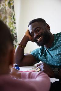 Happy man leaning on elbow while looking at daughter