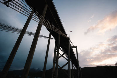 Dramatic low angle view of bridge against sky at sunset
