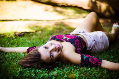 Portrait of smiling teenage girl lying down on grass