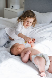 Older sister and baby brother play and the bed. two cute little children siblings playing at home