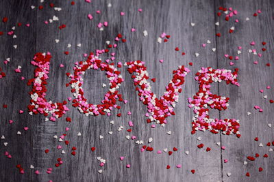 High angle view of love text made with heart shape confetti on table