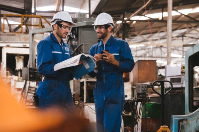 Low angle view of factory workers reading manual in factory