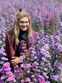 Portrait of smiling young woman against purple flowering plants