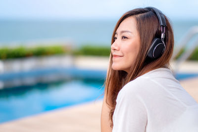 Smiling woman listening to music while sitting outdoors