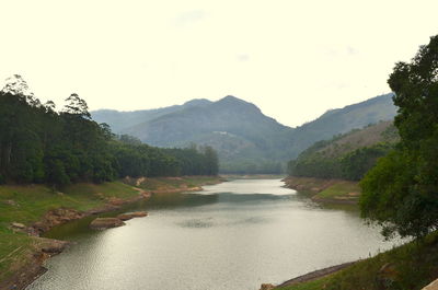 Scenic view of river by mountains against clear sky