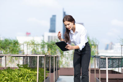 Young woman holding umbrella while standing on railing