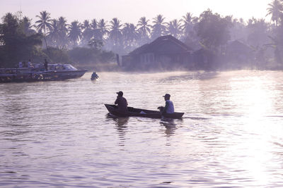 People on boat in lake against sky