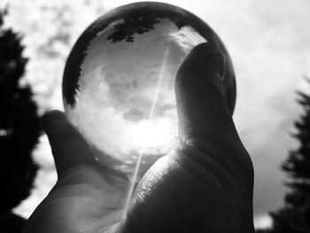 Close-up of human hand against sky