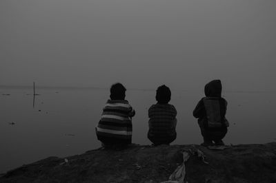 Rear view of people looking at sea against clear sky