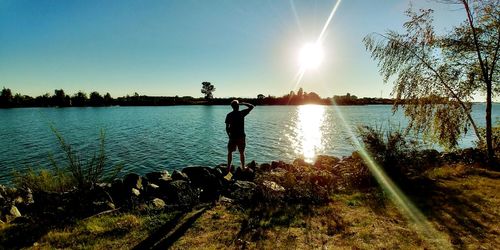 Woman standing by lake against sky