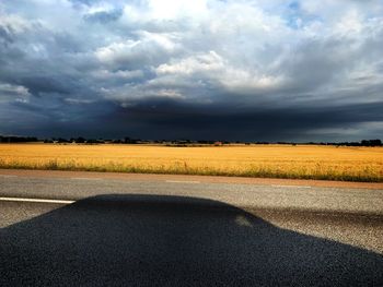 Road amidst field against sky