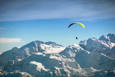 Person paragliding by snowcapped mountains 