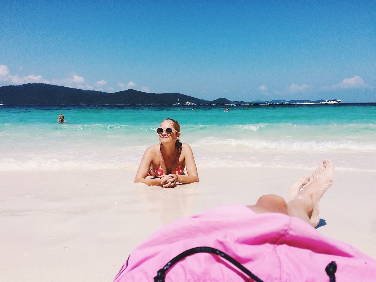 WOMAN SITTING ON BEACH AGAINST SEA