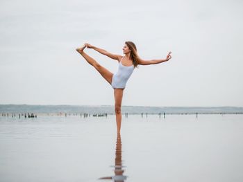 Woman standing in sea against sky