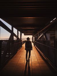 Rear view of silhouette man walking on bridge