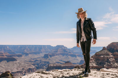 Man standing on rock against sky