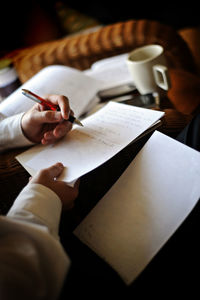 Cropped hand of woman writing on book