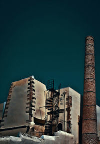 Low angle view of factory against clear sky during winter