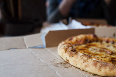 Cropped image of pizza in box against person