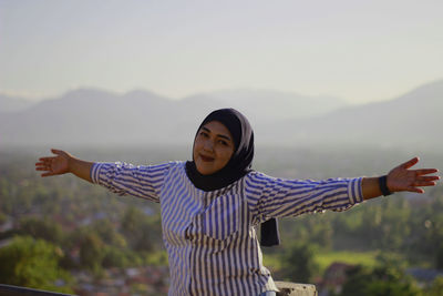 Portrait of young woman standing against sky during sunset