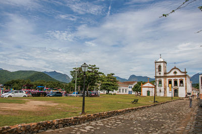 Cobblestone street with old church under restoration and cars in paraty, brazil.