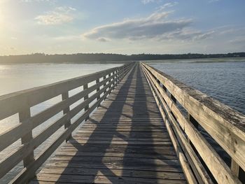 Wooden pier over sea against sky