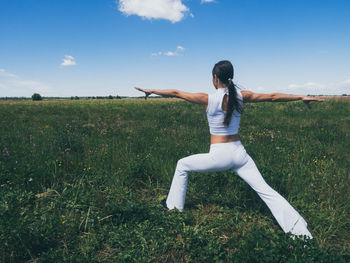 Full length of woman exercising on field