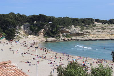 Panoramic view of people on beach against sky