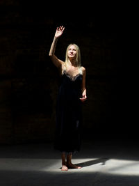 Full length of young woman standing against wall