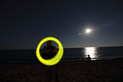 Yellow standing on beach against sky at night