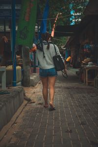 Rear view of woman walking on footpath in city