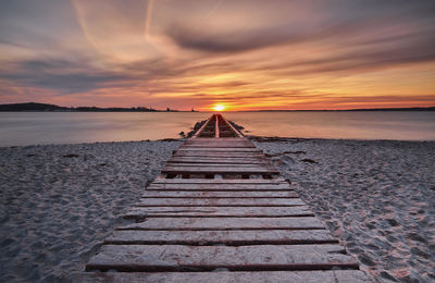 Pier at beach during sunset