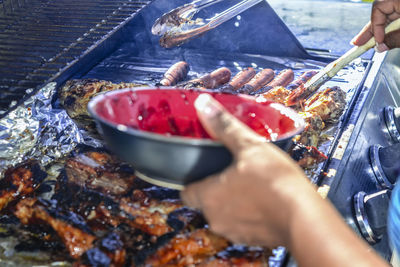 Close-up of person preparing food on barbecue grill 