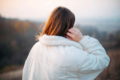 Rear view of woman standing outdoors during winter