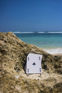 View of rock on beach against clear blue sky