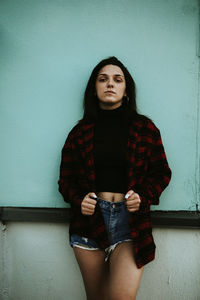 Portrait of a beautiful young woman standing against wall