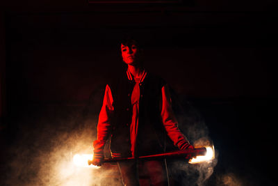 Low angle view of man standing against illuminated fire at night