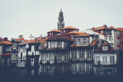 Low angle view of houses by tower against sky