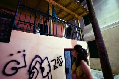 People standing by graffiti on wall