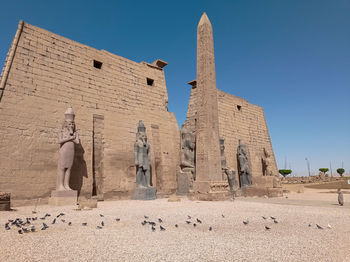 Ancient egyptian temple with an obelisk and statues of old pharaohs