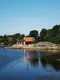 House by lake and building against sky