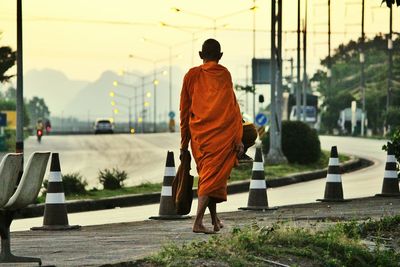 Rear view of monk walking on sidewalk