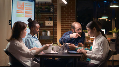 Side view of woman using mobile phone while sitting at restaurant