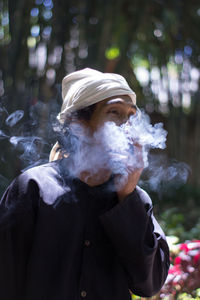 Woman standing by smoke emitting from while looking at camera