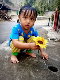 Portrait of cute boy with flower petals on floor