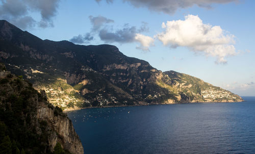 Scenic view of sea by mountains against sky