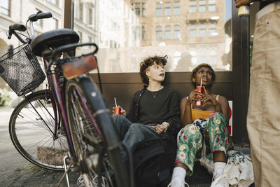 Friends sitting with bicycle in city