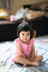 Portrait of cute girl sitting on bed