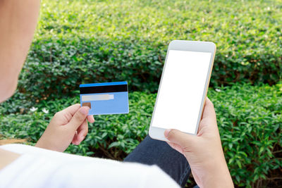 Midsection of person holding mobile phone in park